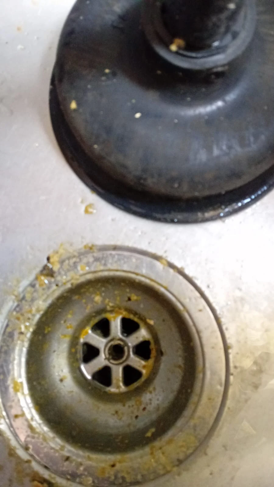 Close-up of a blocked waste outlet with residue around the drain opening.